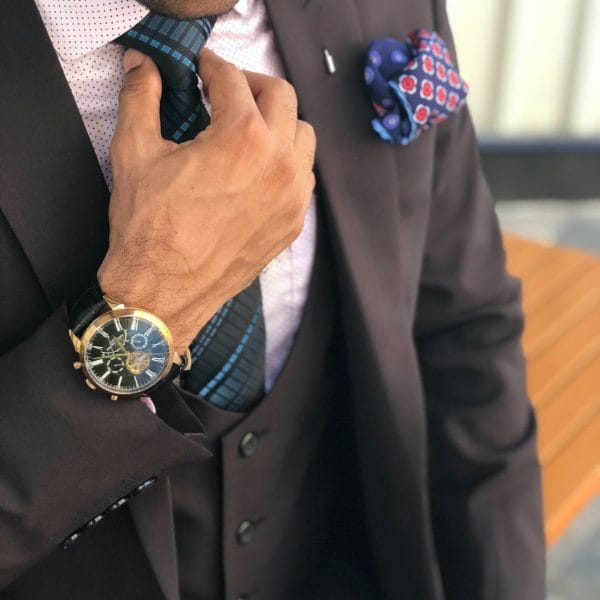 man in formal suit jacket holding his necktie