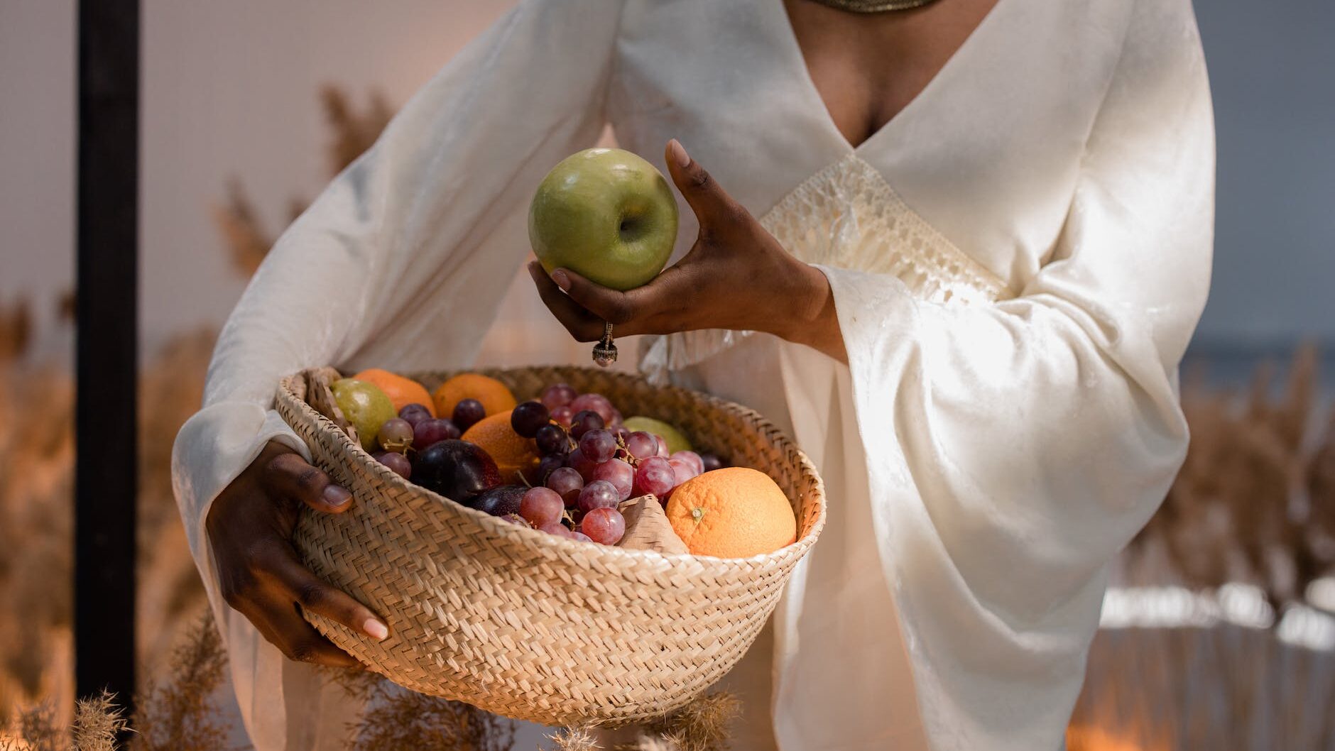 a woman in white long sleeves holding a green apple
