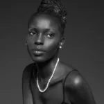 Monochrome portrait of a Black woman with an updo hairstyle, wearing a pearl necklace and spaghetti strap top