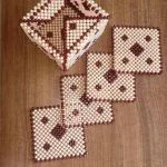 Geometric patterned beaded coasters in white and brown on a wooden surface