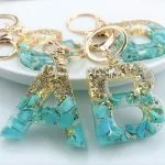 Decorative keychains with letters A and B made of resin with turquoise stones and gold flakes